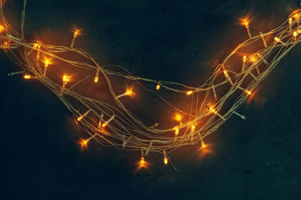 Ilık ışıklandırılmış çelenk koyu arkaplanı kapatır