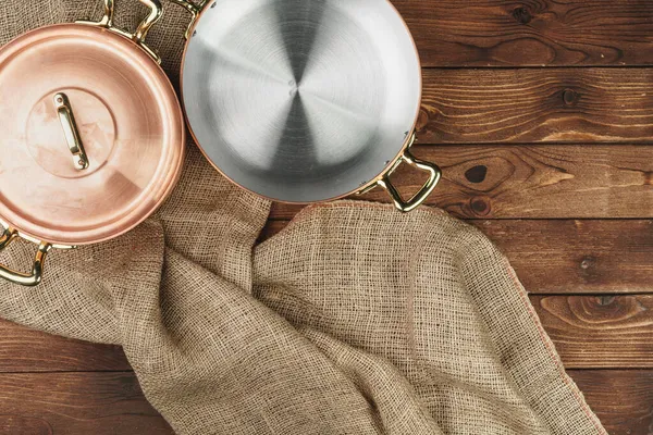 Koyu ahşap masada bakır tencere, üst manzara.