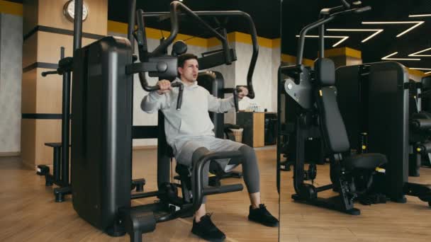 Hombre joven con capucha gris brazos de entrenamiento en un gimnasio — Vídeos de Stock