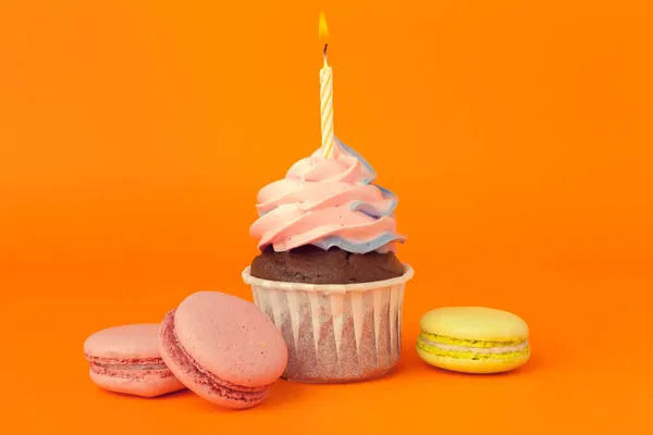 Cupcake com velas de aniversário no fundo laranja — Fotografia de Stock