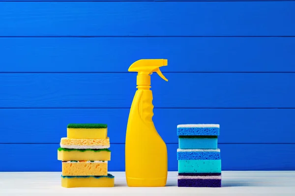 Упаковка новых моющих губок и жидкого моющего средства на синем деревянном фоне — стоковое фото