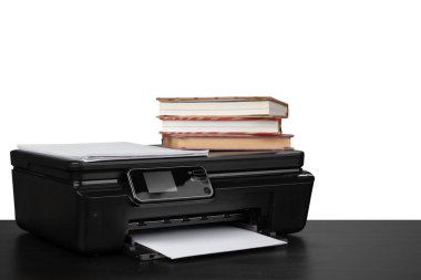 Yazıcı ile çalışma masası ve beyaz çekmeceler üzerine istiflenmiş kitaplar