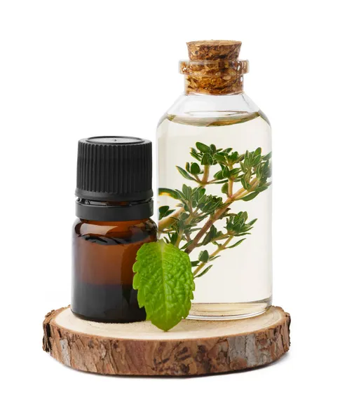 Óleo essencial em uma pequena garrafa com folha verde sobre fundo branco — Fotografia de Stock