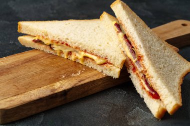 Jambonlu sandviç, koyu gri arka planda peynir.