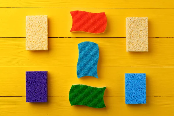Cleaning sponges on yellow wooden background flat lay — Stock Photo, Image