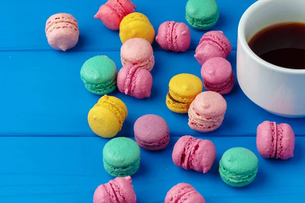 Xícara de café e macarons coloridos em fundo de madeira azul — Fotografia de Stock