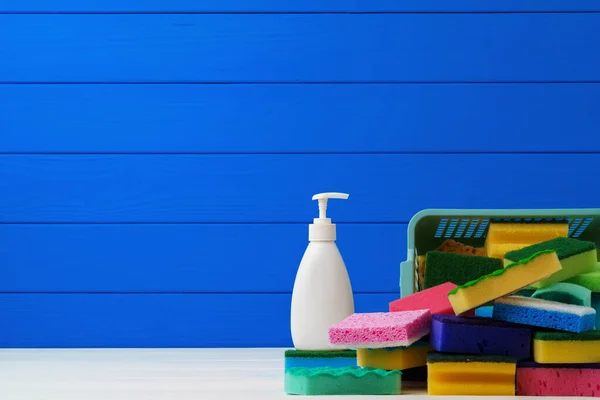Упаковка новых моющих губок и жидкого моющего средства на синем деревянном фоне — стоковое фото