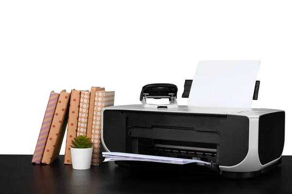 Printer and stack of books on black table against white background — Stock Photo, Image