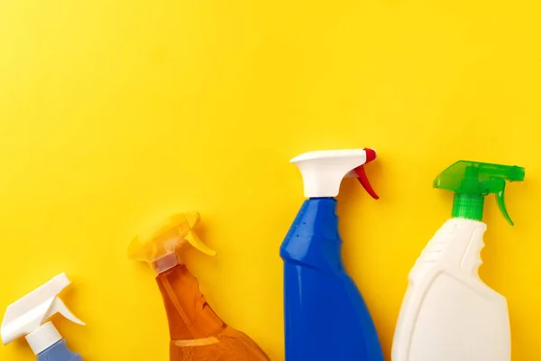 Очистка бутылок с моющим средством на желтом фоне — стоковое фото