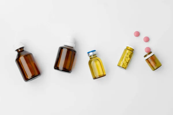 Маленькие стеклянные бутылки с лекарствами на белом фоне — стоковое фото