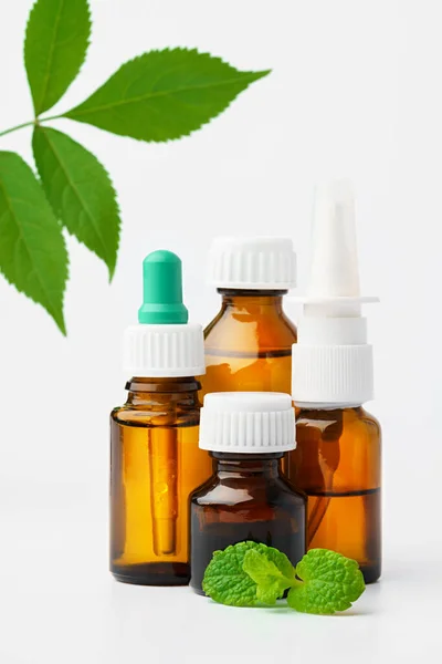 Aceite esencial en una pequeña botella con hoja verde sobre fondo blanco — Foto de Stock