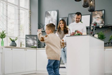 Mutlu genç aile Noel 'de evde, mutfakta birlikte vakit geçiriyor.