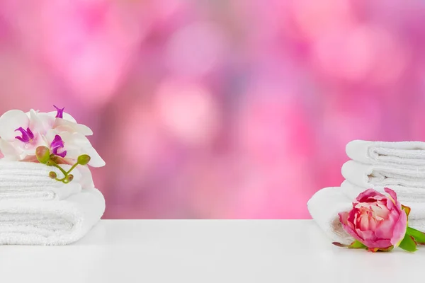 Toallas con flores sobre mesa ligera sobre fondo borroso — Foto de Stock