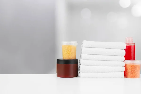 Spa still life with towels and skincare cosmetics against blurred background — Stock Photo, Image