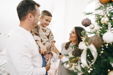 Evde Noel ağacı süsleyen 3 kişilik bir aile.