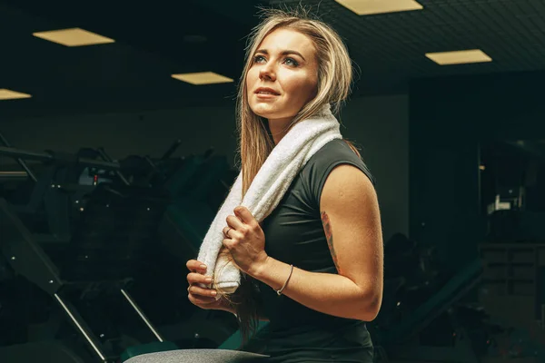 Giovane donna con asciugamano seduta e riposante in palestra — Foto Stock