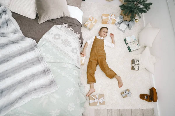 Niño pequeño con regalos de Navidad acostado en el suelo — Foto de Stock