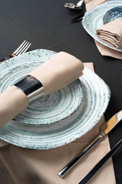 Masa ayarı. Siyah tabloda soyut desenli plakalar