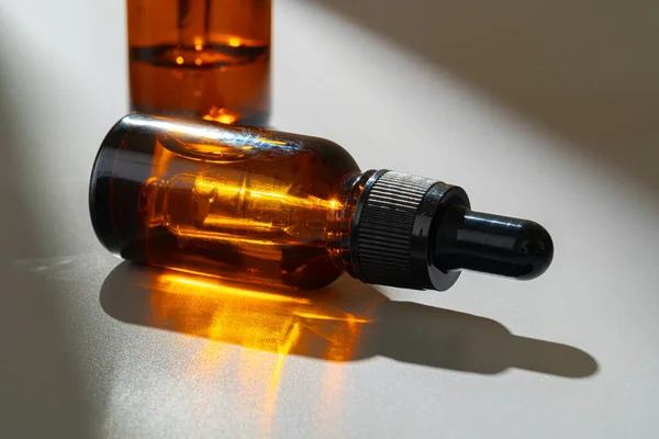 Butelki ze szkła bursztynowego do kosmetyków, medycyny naturalnej lub olejków eterycznych na szarym tle — Zdjęcie stockowe