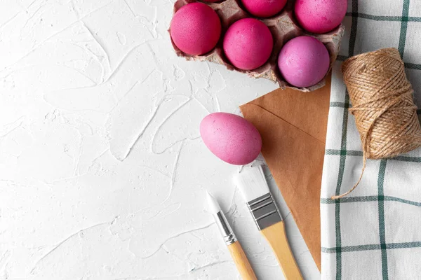 Pintura de huevos de Pascua en rosa sobre mesa blanca, vista desde arriba — Foto de Stock