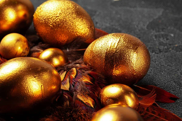 Kırmızı kuş tüyleri üzerinde altın Paskalya yumurtaları — Stok fotoğraf
