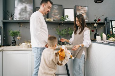 Mutlu genç aile Noel 'de evde, mutfakta birlikte vakit geçiriyor.