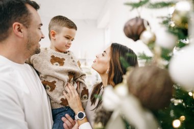 Evde Noel ağacı süsleyen 3 kişilik bir aile.