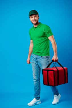 Mavi arka planda termal çantalı teslimatçı.