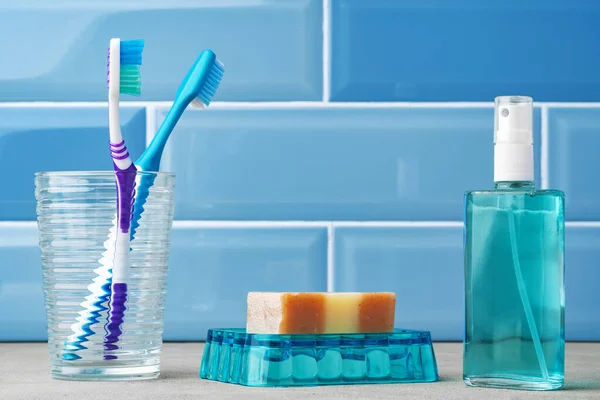 As escovas de dentes em um copo no banheiro azul. — Fotografia de Stock
