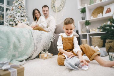 Mutlu küçük çocuk evde Noel hediyelerini açıyor.