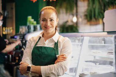 Kahve tezgahının içinde duran genç bayan barista.