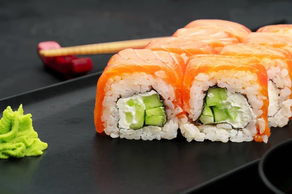 Rouleau de sushis fraîchement servi sur une assiette noire — Photo