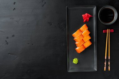 Siyah tabakta servis edilen taze Philadelphia suşi rulosu.