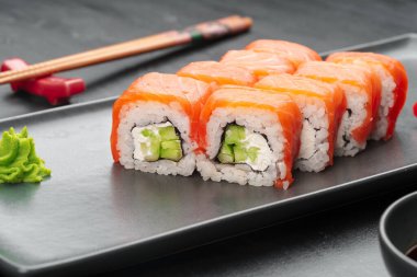 Siyah tabakta servis edilen taze Philadelphia suşi rulosu.