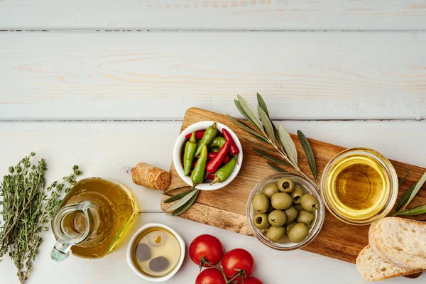 Оливкова олія, оливки та помідори на дерев'яному фоні — стокове фото