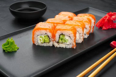 Siyah tabakta servis edilen taze Philadelphia suşi rulosu.