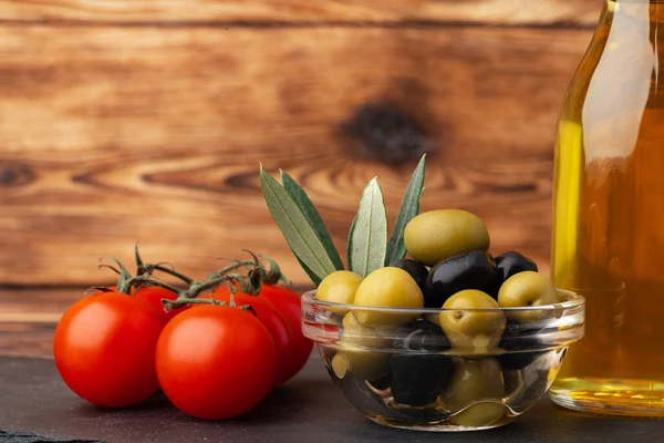 Ahşap zemin üzerinde zeytinyağı, zeytin ve domates.