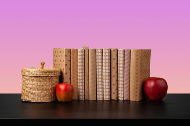 Siyah ahşap masada yığınla kitap.