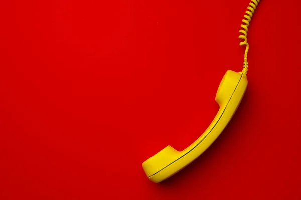 Telefono fisso giallo su sfondo rosso vista dall'alto — Foto Stock