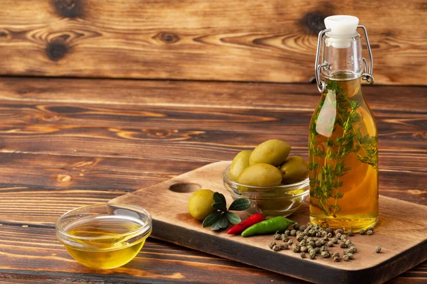 Olijven en fles olijfolie op houten ondergrond — Stockfoto