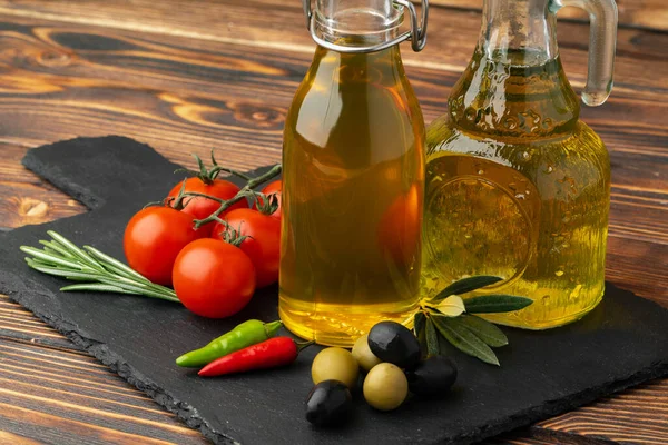 Olijfolie, olijven en tomaten op houten ondergrond — Stockfoto