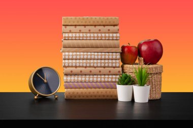 Siyah ahşap masada yığınla kitap.