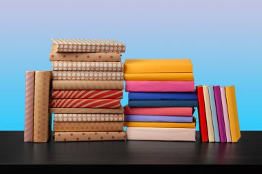Siyah ahşap masada yığınla kitap.