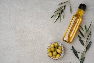 Gri zemin üzerinde zeytin yağı olan cam şişe.