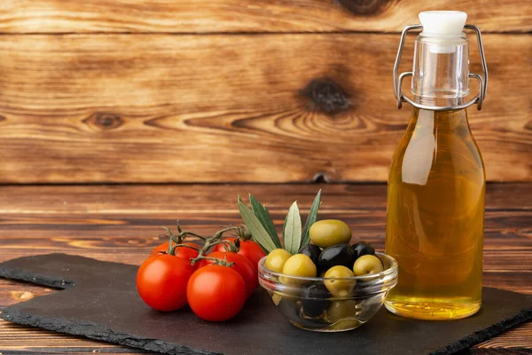 Aceite de oliva, aceitunas y tomates sobre fondo de madera — Foto de Stock