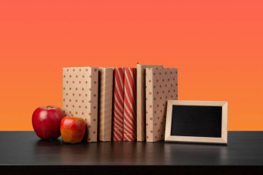 Siyah ahşap masada yığınla kitap.