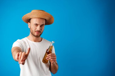 Genç adam elinde bir şişe bira tutuyor ve dur işareti veriyor.