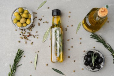 Gri zemin üzerinde zeytin yağı olan cam şişe.