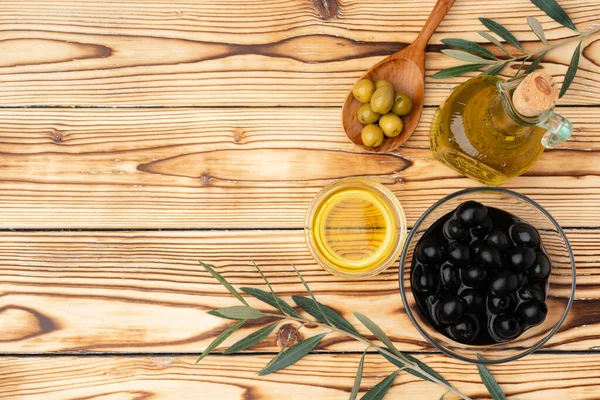 Ahşap zemin üzerinde zeytin ve bir şişe zeytin yağı.