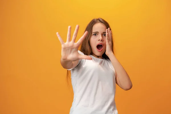 Налякана молода дівчина-підліток показує стоп жест на жовтому тлі — стокове фото
